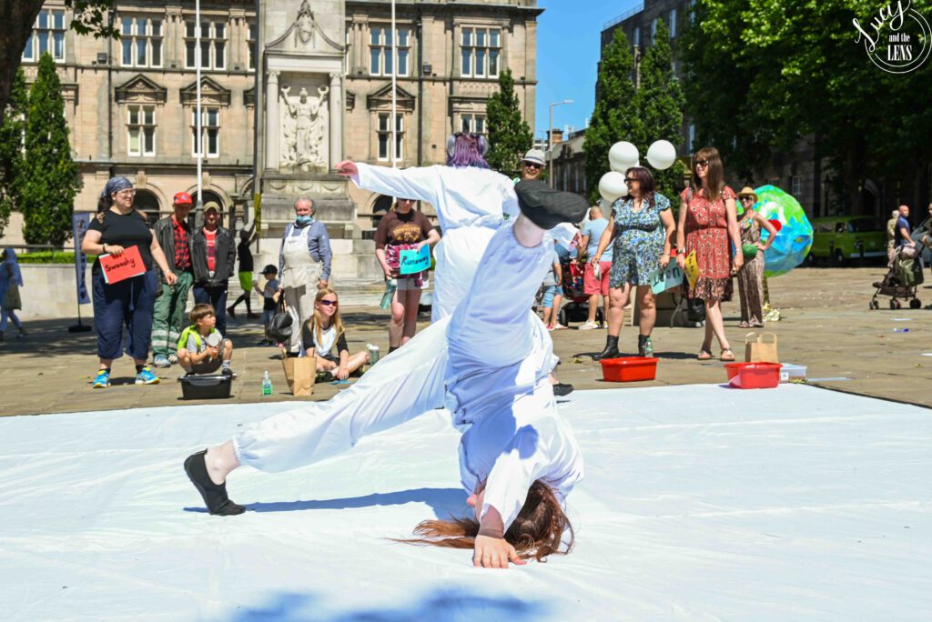 Image of Alissa in a white boiler suit doing a shoulder stand